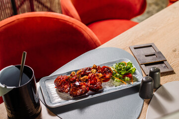 Appetizing baked chicken legs with raspberry sauce in a restaurant on the table