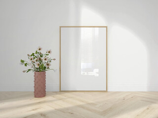 Vertical wooden frame mockup on wooden floor with decorative plant and pink vase. Empty poster...