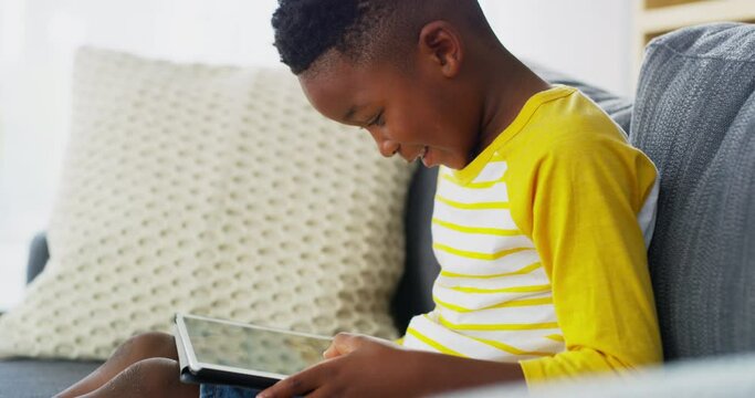 Tablet, online and child on sofa in home for watching movies, internet games and streaming cartoons. Online, winner and young boy on digital technology for website, elearning and relax in living room