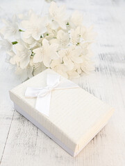 Still life, a bouquet of white flowers and a gift box on a light wooden background