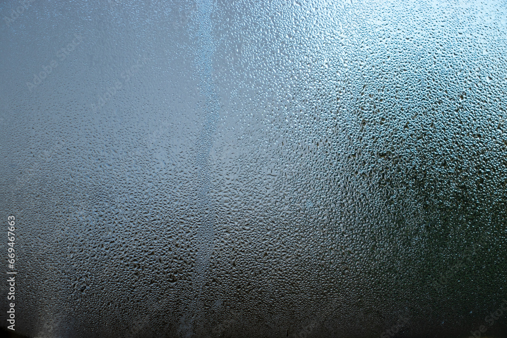 Poster close-up image of water droplets creating patterns on clear glass.