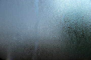  Close-up image of water droplets creating patterns on clear glass.