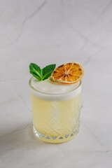 Refreshing yellow cocktail with mint and citrus on a bright background