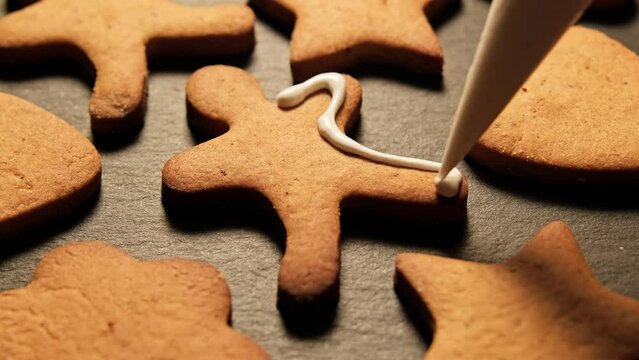 Decoration of homemade gingerbread Christmas cookies with food icing glaze. New year food concept. Gingerbread man. Close-up in 4K, UHD