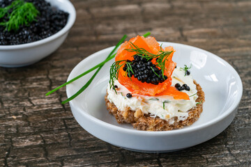 Cocktail canapes with smoked salmon, cream cheese and caviar on rye bread - gourmet party food.