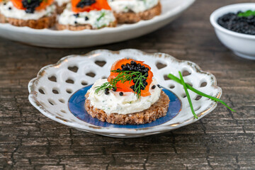 Cocktail canapes with smoked salmon, cream cheese and caviar on rye bread - gourmet party food.