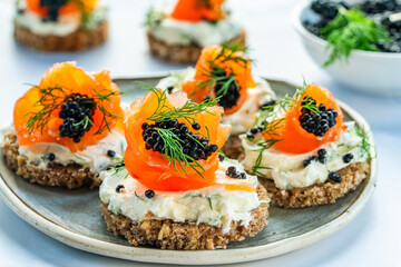 Cocktail canapes with smoked salmon, cream cheese and caviar on rye bread - gourmet party food.