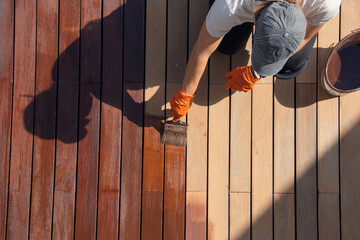 Exterior wood deck sealing and staining, overhead worker applying protective deck stain color