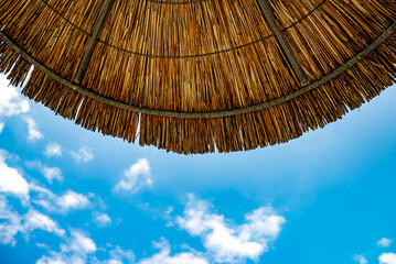 Sky with clouds under straw bamboo umbrella. © M-Production