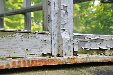 Wooden window frame damaged paint. Old window frame needing replacement. Paint job required. Old paint flaking. House maintenance needed concept.