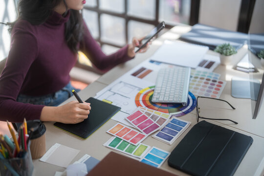 Graphic designer freelance women thinking creative ideas and using digital tablet to sketching logo brand while working to designing about graphic design with technology equipment in home studio - Powered by Adobe