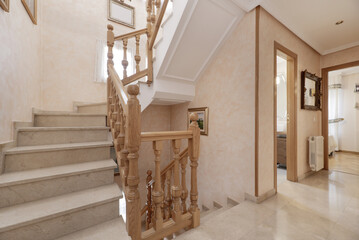 Stairs with wooden railing in a multi-storey detached house with cream-coloured polished marble floors and steps