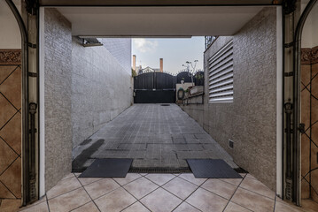 Entrance portal to a garage of a single-family home with access ramp and gate with folding metal...