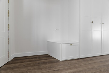 Hallway of a home with custom-made white wooden cabinets with wooden floors and smooth walls