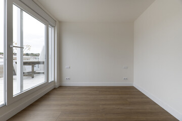 Panoramic view of a living room with wooden floors and access to a terrace in an apartment through a glass partition