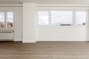 Wall full of windows with views of a living room with wooden floors and plain white painted walls