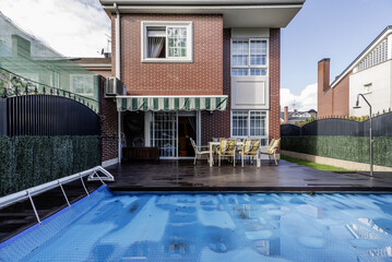 Obraz premium Backyard of a single-family home with a swimming pool covered by a protective tarp, acacia wood floors