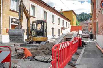 Construction Area with Operator digging with red safety barriers and excavator