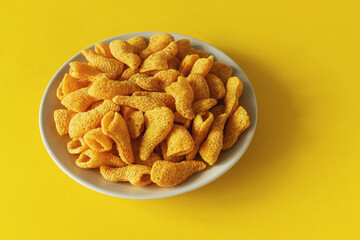 Ham flavored chips snacks on a plate on a yellow background