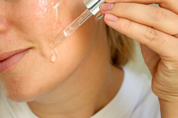 Close up of woman using moisturising skin serum on her face