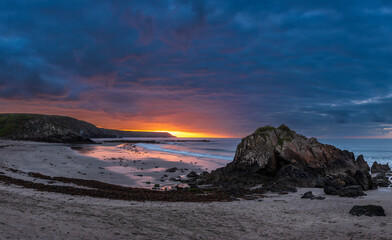 Beautiful sunrise landscape image of Kennack Sands in Cornwall UK wuth dramatic moody clouds and vibrant sunburst