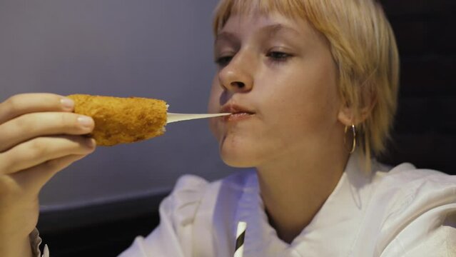 A teenage girl takes with her hands and eats hot cheese sticks with sauce. Close-up.