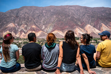 Amigos sentados en el mirador de Maimará admirando los cerros coloridos - obrazy, fototapety, plakaty