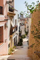 Narrow street with stairs in Barrio Santa Cruz in Alicante, Costa Blanca, Spain.