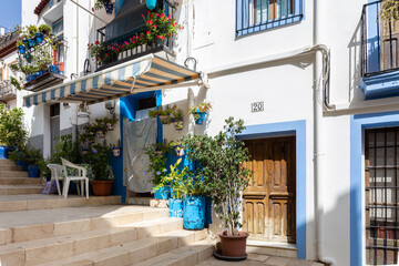 Fototapeta na wymiar Blue and white houses in typical street in Barrio Santa Cruz in Alicante, Costa Blanca, Spain