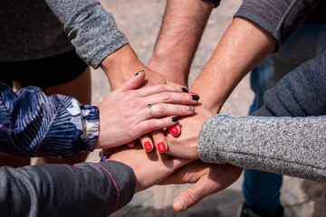 Grupo de personas agrupando sus manos en señal de trabajo de equipo - obrazy, fototapety, plakaty