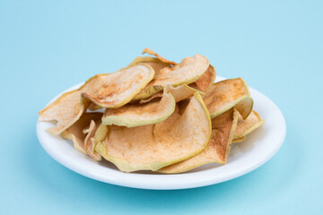 Sliced, dried apples in a plate isolated on blue background. Homemade organic apple.