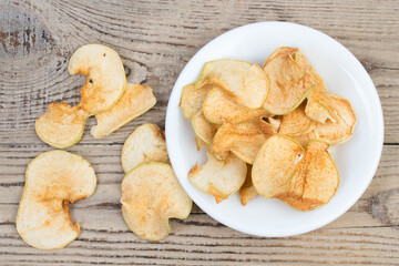 Sliced, dried apples in a plate isolated on wooden background. Homemade organic apple.