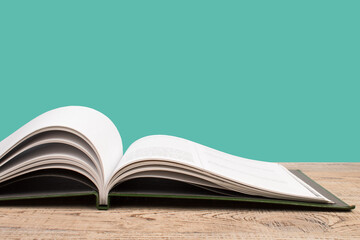 open book. Composition with hardback books, fanned pages on wooden deck table and green background. Books stacking. Back to school. Copy Space. Education background.