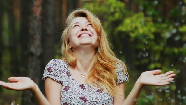 Portrait of happy romantic blonde woman in summer dress blowing dandelion seeds slow motion no allergies 