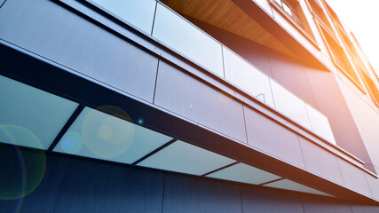 A view at a straight facade of a modern building with a dark grey facade. Dark grey metallic panel...