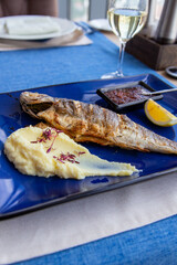 Seabass baked with vegetables, lemon and mashed potatoes on plate