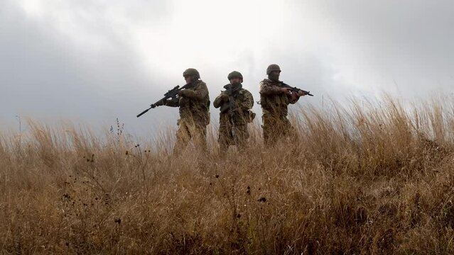 Military men with weapons on an open-air field. Concept of military operations and armed forces.