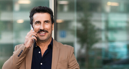 Happy successful mature businessman talking on smartphone