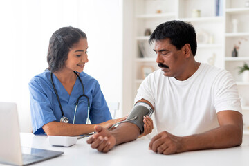 Indian Doctor Woman Checking Blood Pressure To Male Patient In Clinic