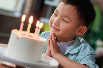 A little boy wishing on a birthday cake