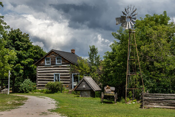 Fototapeta na wymiar old log cabin and windmill with stormy skies. Kawarthas settlers village, bobcaygeon, ontario