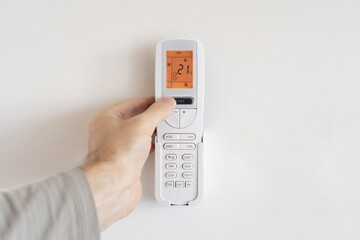 A man presses the power button on a remote control for an air conditioner.