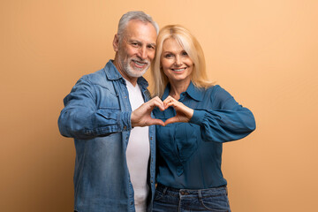 Happy retired man and woman showing heart gesture