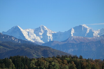 World famous mountains Eiger, Monch and Jungfrau covered with snow, blue sky in the background