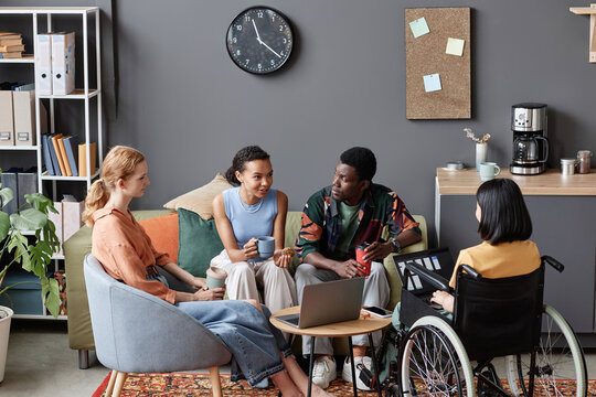 Diverse group of young professionals meeting in office lounge and discussing projects
