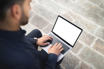 Unrecognizable arab businessman surfing on laptop with blank screen outside