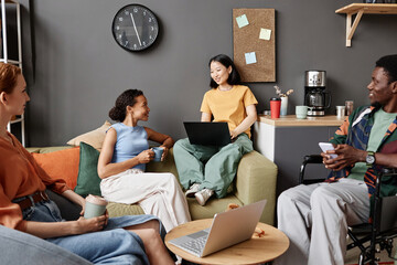 Diverse group of young professionals meeting in office lounge and discussing projects