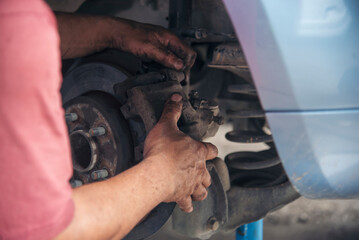 Close up Car Mechanic man hands repairing car auto repair shop. Man hands fixing machinery vehicle...