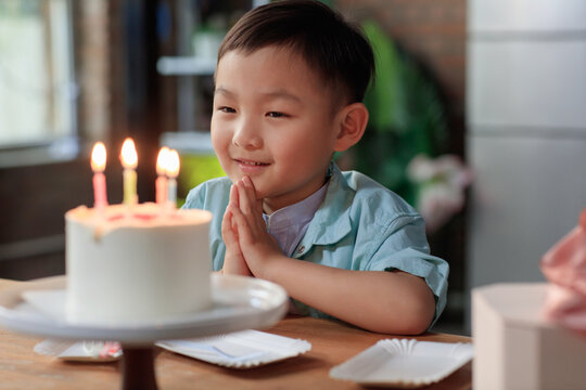 A little boy wishing on a birthday cake