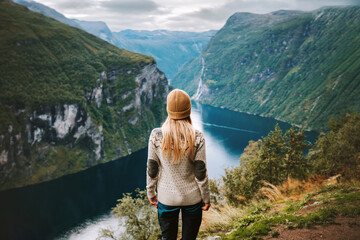 Woman traveling in Norway alone sightseeing Geiranger fjord view adventure lifestyle vacations outdoor scandinavian trip healthy lifestyle eco tourism - obrazy, fototapety, plakaty
